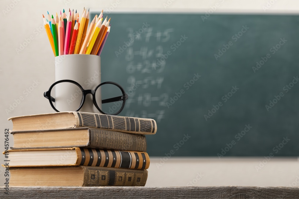 Stack of books and school blackboard