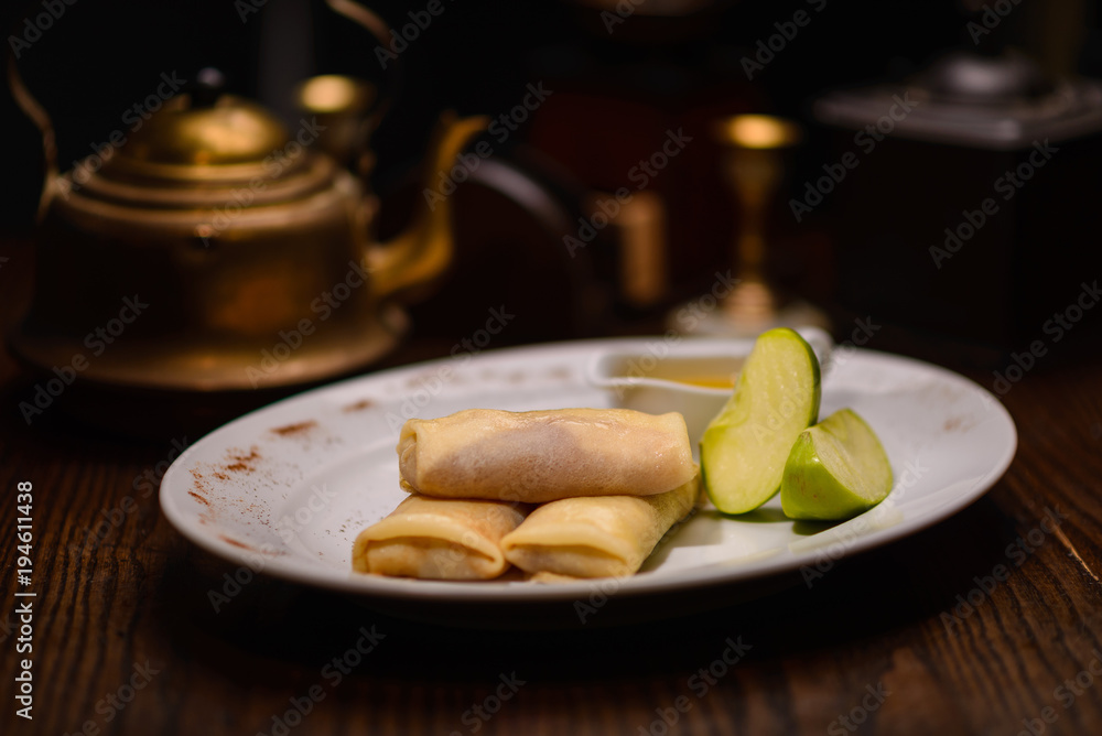 有馅料和一个绿苹果的煎饼，背景是一个水壶