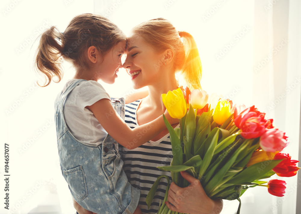 happy mothers day! child daughter   gives mother a bouquet of flowers to tulips.