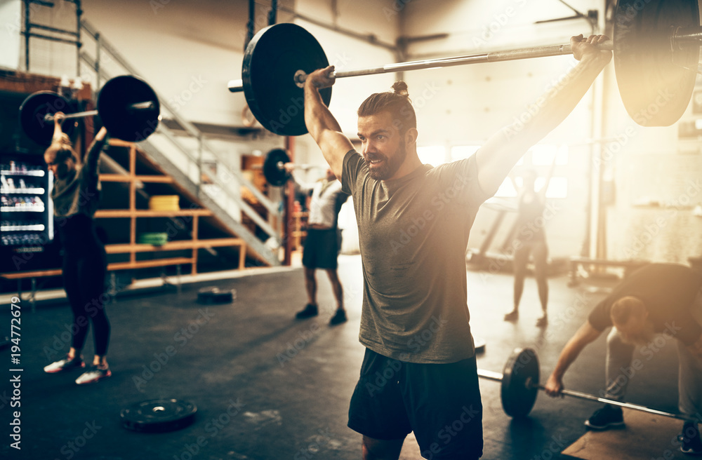 Fit young man weight training in a gym class