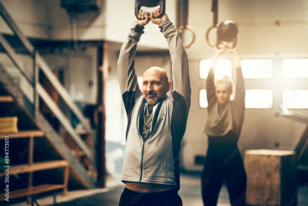 Mature man swinging weights during a gym exercise class