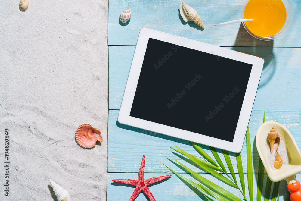 Summer beach vacation accessories and digital tablet on blue background.