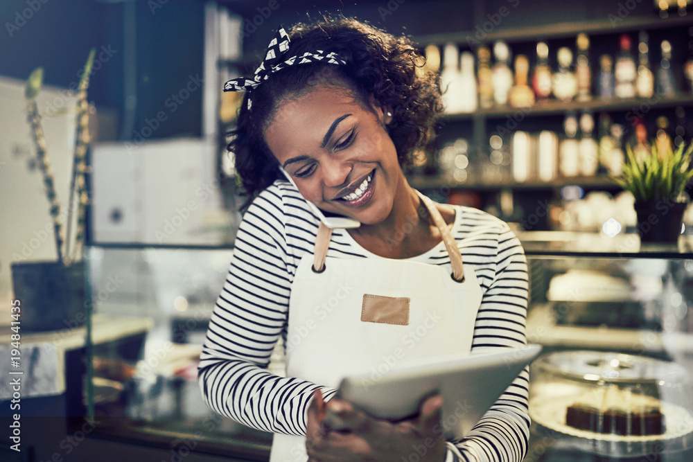 Smiling young African entrepreneur busy working in her cafe