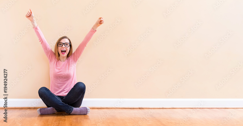 Happy young woman cheering with her arms in the air