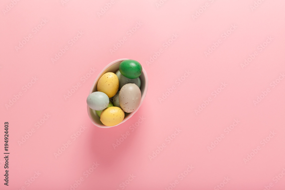 Painted Easter eggs in a basket on a pink background