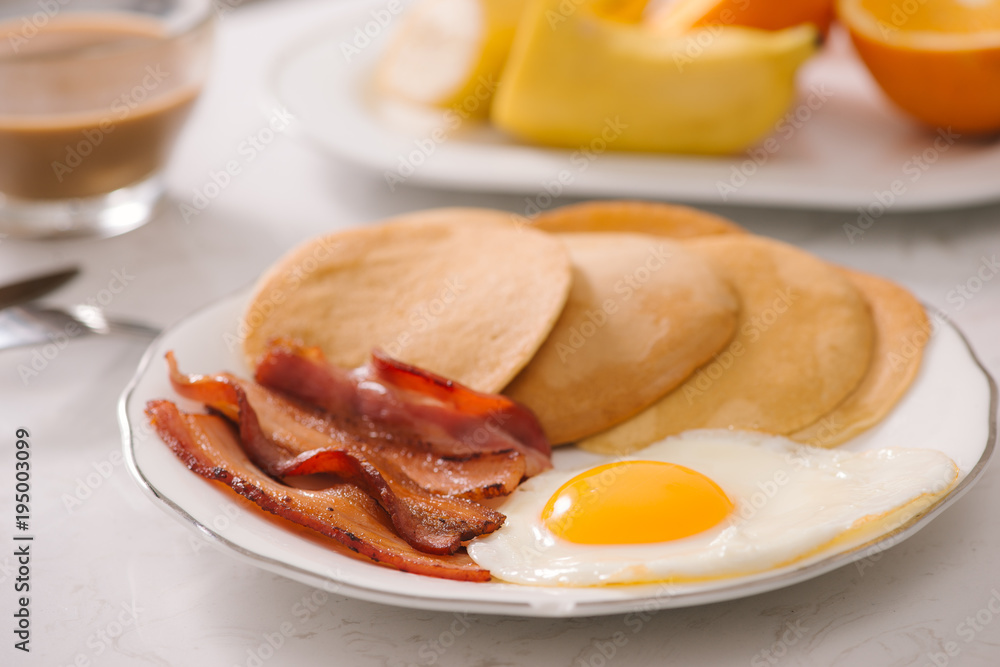 Breakfast plate with pancakes, eggs, bacon and fruit.