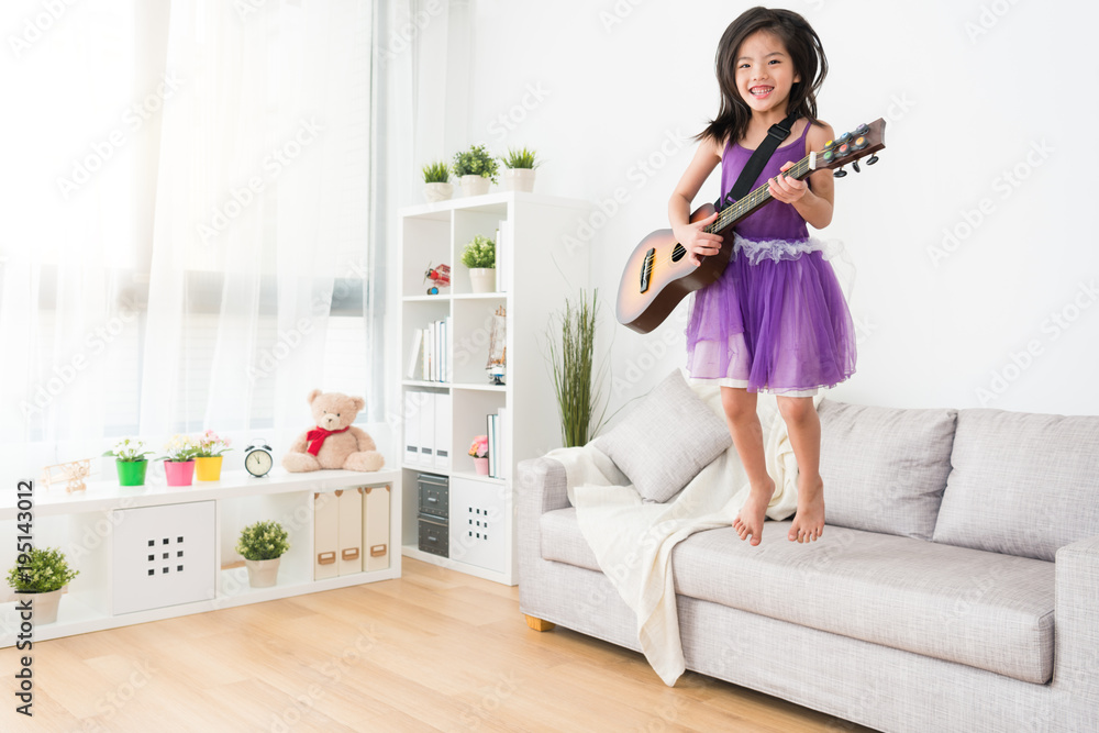 Female kid jump on the sofa.