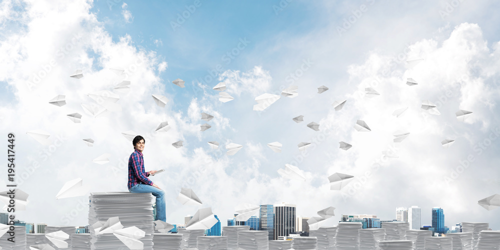 Attractive man sitting on pile of paper documents.