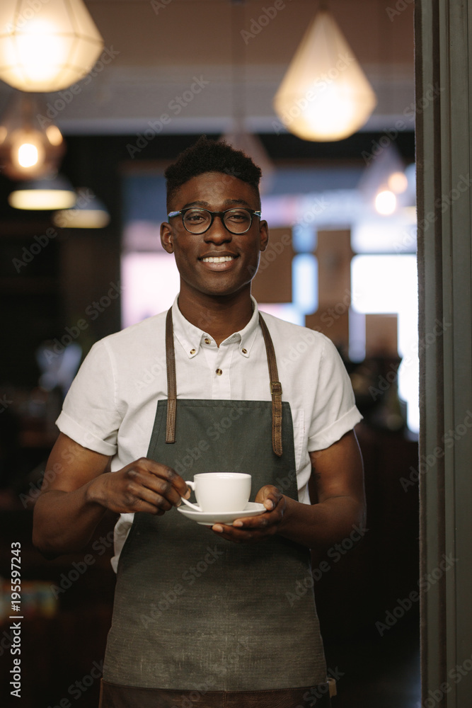 Café owner at his coffee shop holding a coffee cup