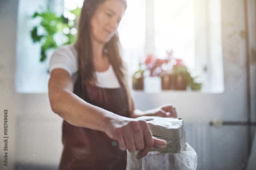 艺术家在她的陶器作坊里切割一块粘土