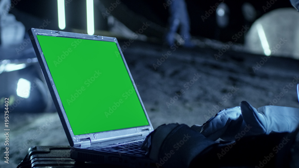 Astronaut on the Alien Planet Works on a Mock-up Green Screen Laptop. In the Background Her Crew Mem