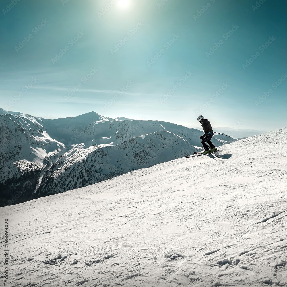 Nice mountains view at sunny day with skiers under blue sky with