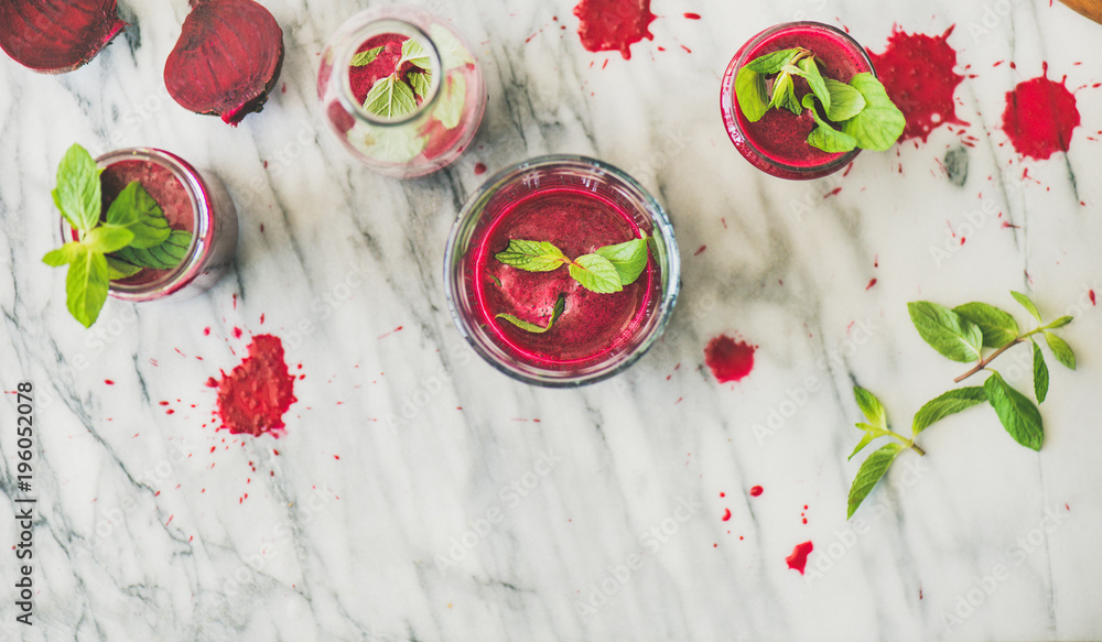 Fresh morning beetroot smoothie or juice in glasses with mint leaves over grey marble background, co