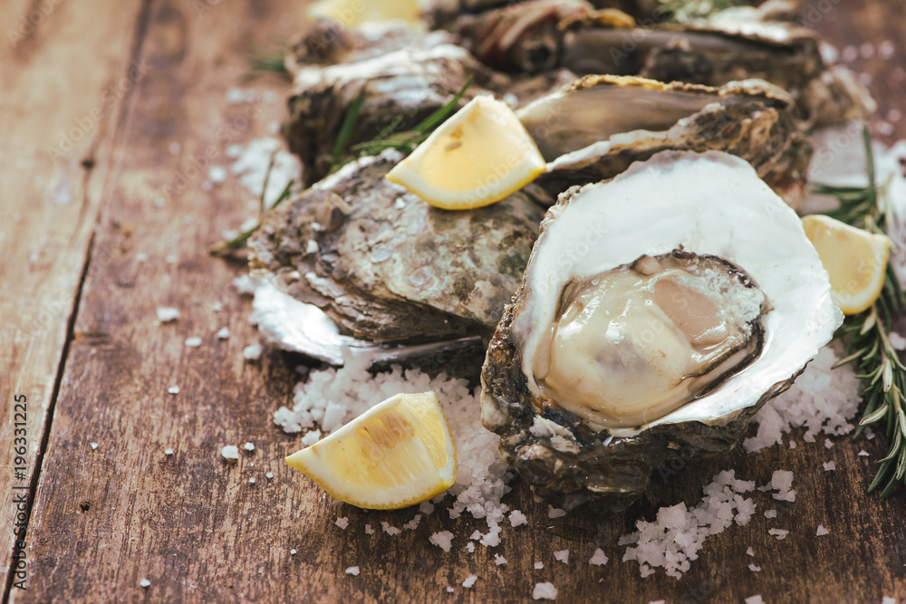 A photo of freshly opened oysters on a wooden background texture with copyspace