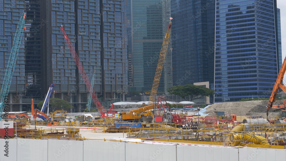 Bustling construction site full of people and machinery near business offices