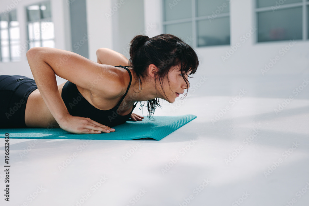 Strong woman doing push ups in gym