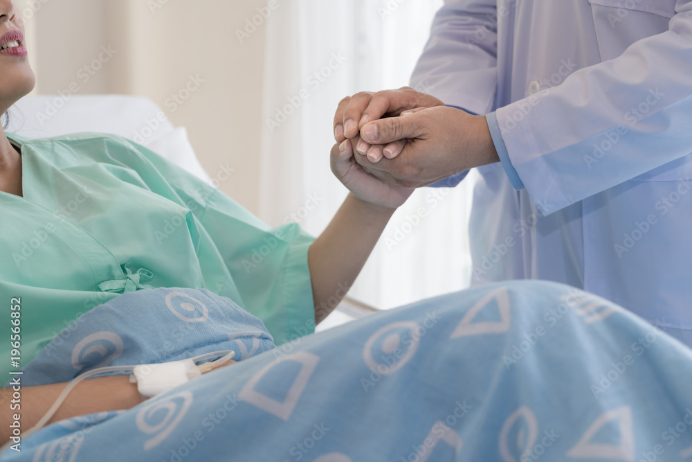 Friendly man doctor hands holding patient hand sitting at the desk for encouragement, empathy, cheer