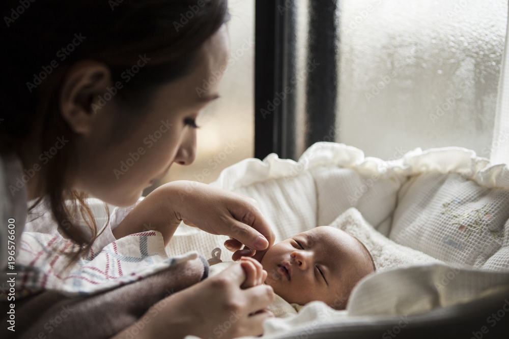 母親が昼寝する子供の様子を見ている