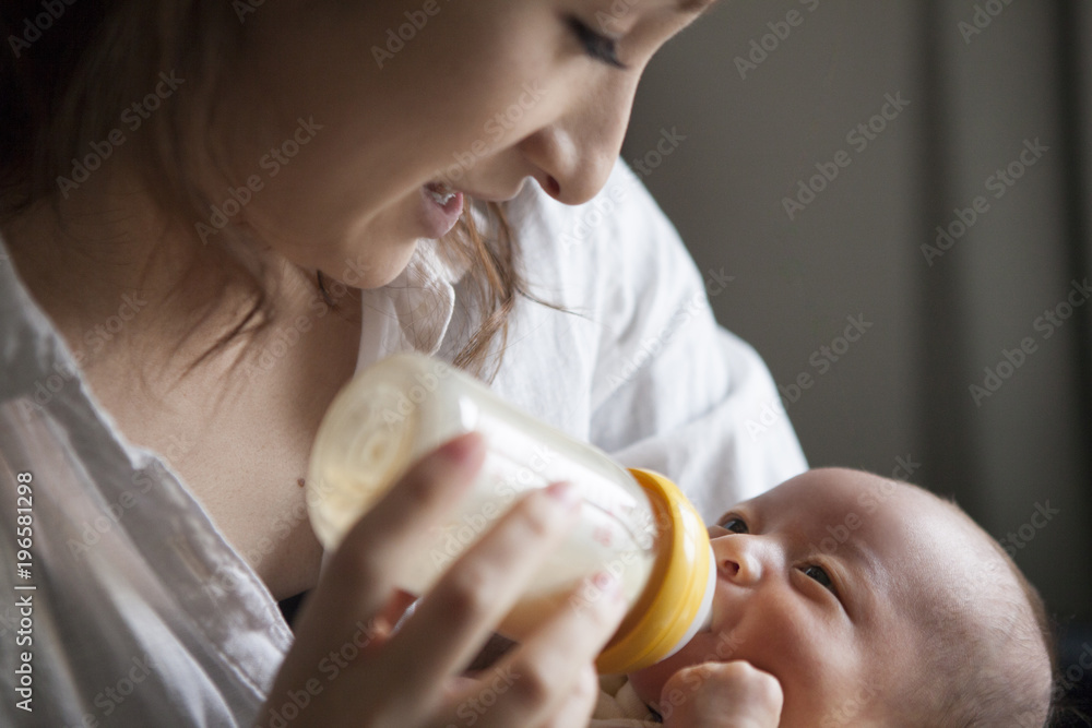 子供に哺乳瓶でミルクを与える母親