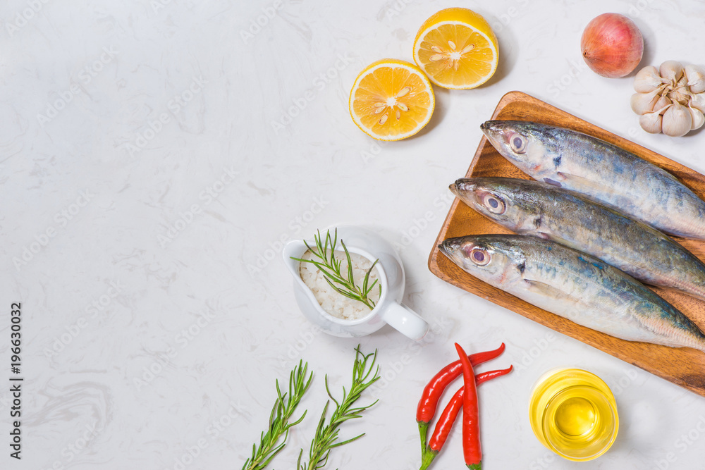 Fish dish cooking with various ingredients. Fresh raw fish decorated with lemon slices and herbs on 