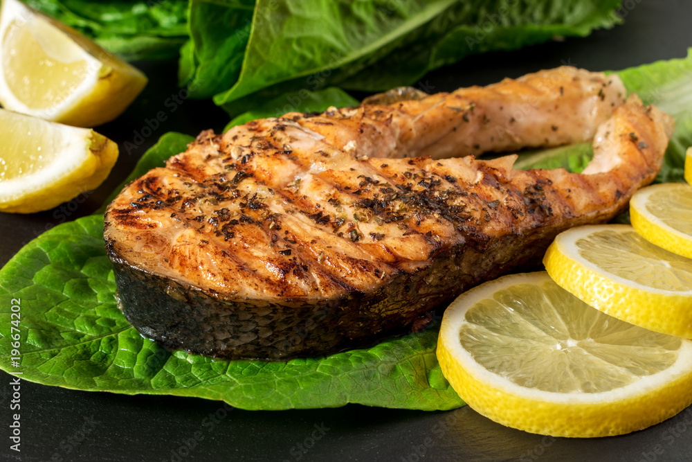 Salmon fillet. Grilled salmon with herb and lemon on black slate board.