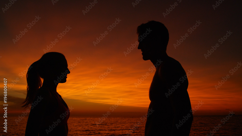 CLOSE UP: Smiling couple looks deep into each others eyes on summer evening.