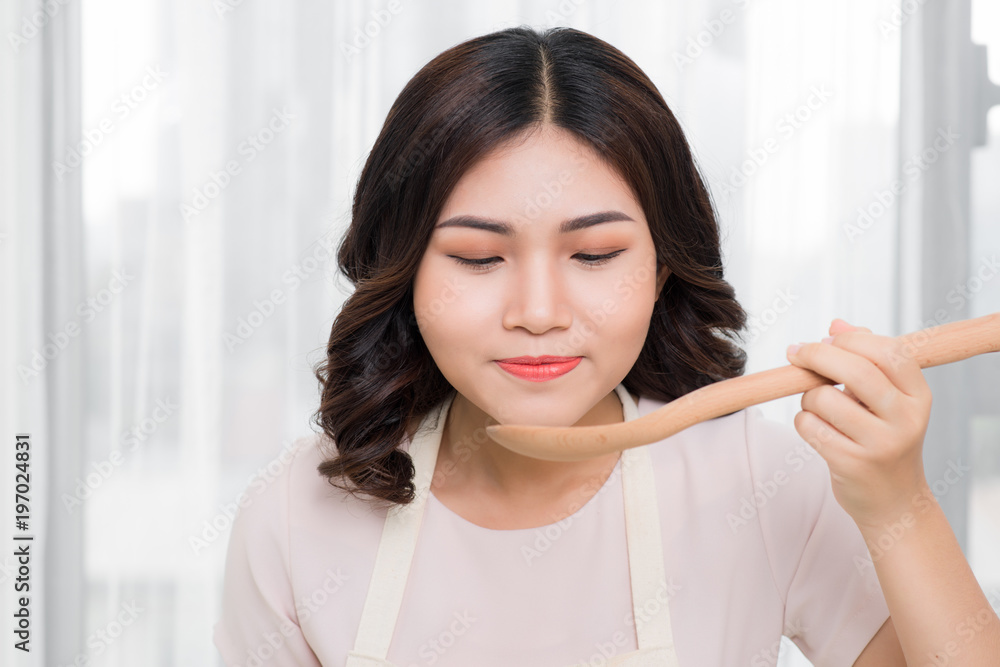 美丽的年轻女子在家用蔬菜煮汤的肖像。