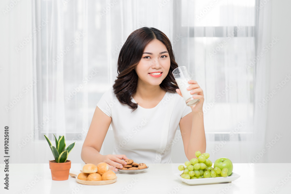 健康女性正在饮用白底隔离玻璃杯中的牛奶。