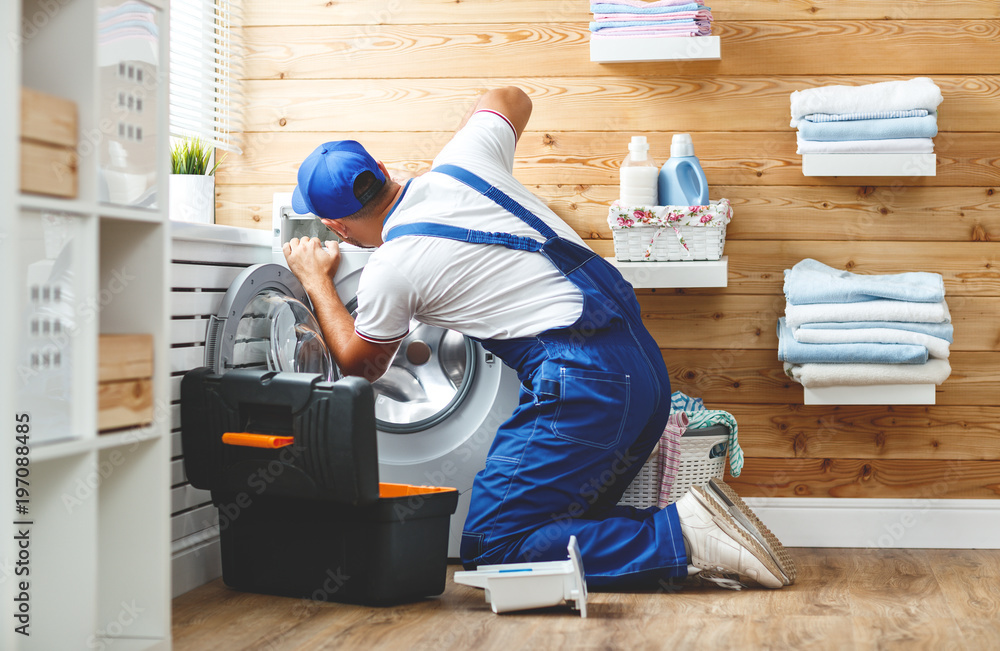 working man   plumber repairs  washing machine in   laundry.