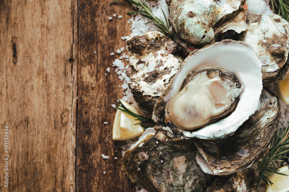 A photo of freshly opened oysters on a wooden background texture with copyspace