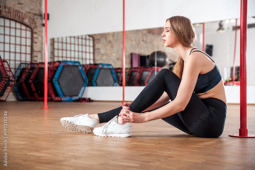 Injured woman feeling pain in her ankle at fitness gym