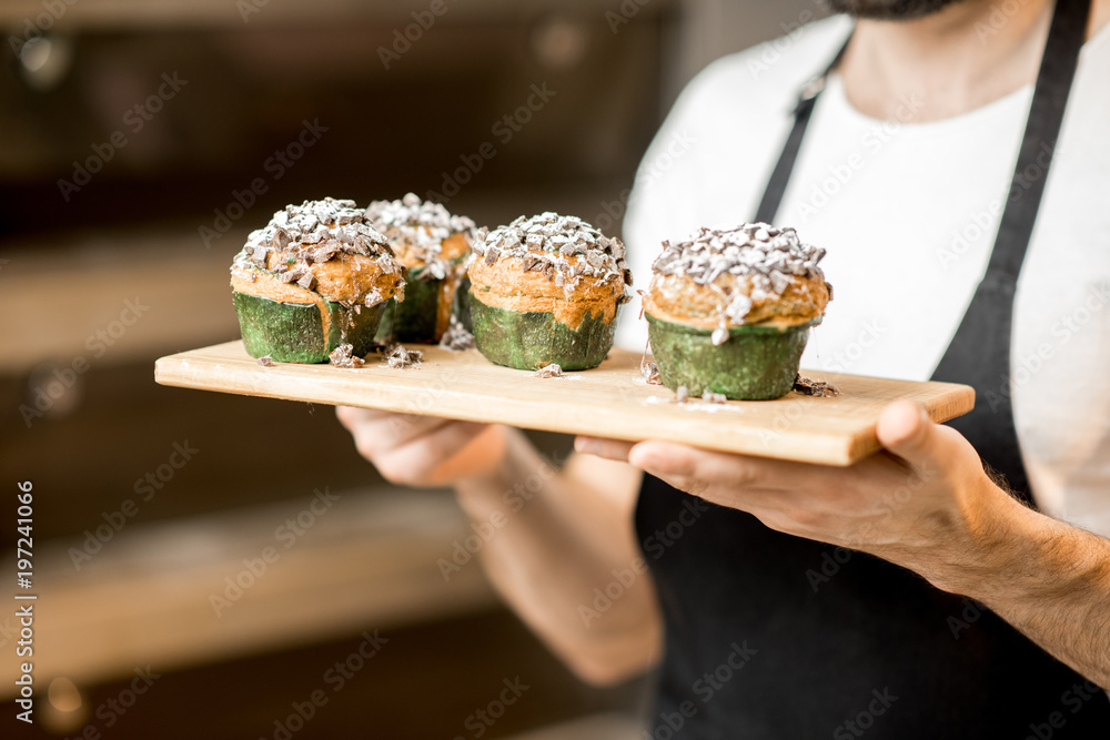 在面包店的专业烤箱背景上，糖果手拿着美味的松饼