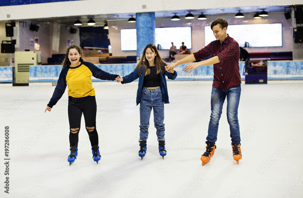 Group of teenage friends ice skating on the ice rink together