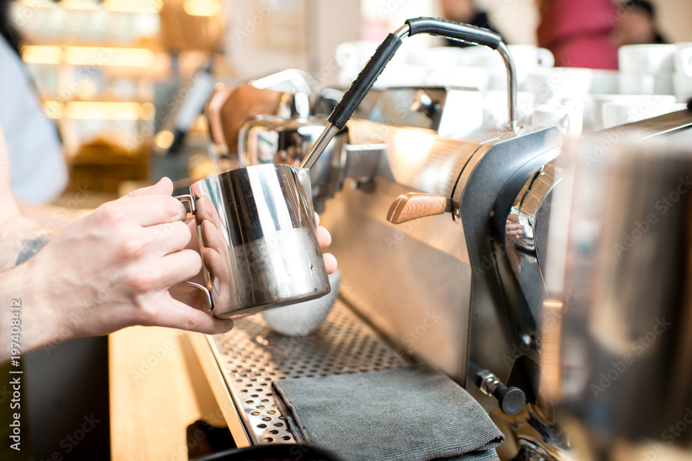 Barista whipping a milk for capucciono with professional coffee machine