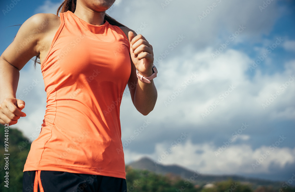 An asian woman athletic is jogging on the concrete road, she is warming her body and tideten her tyi