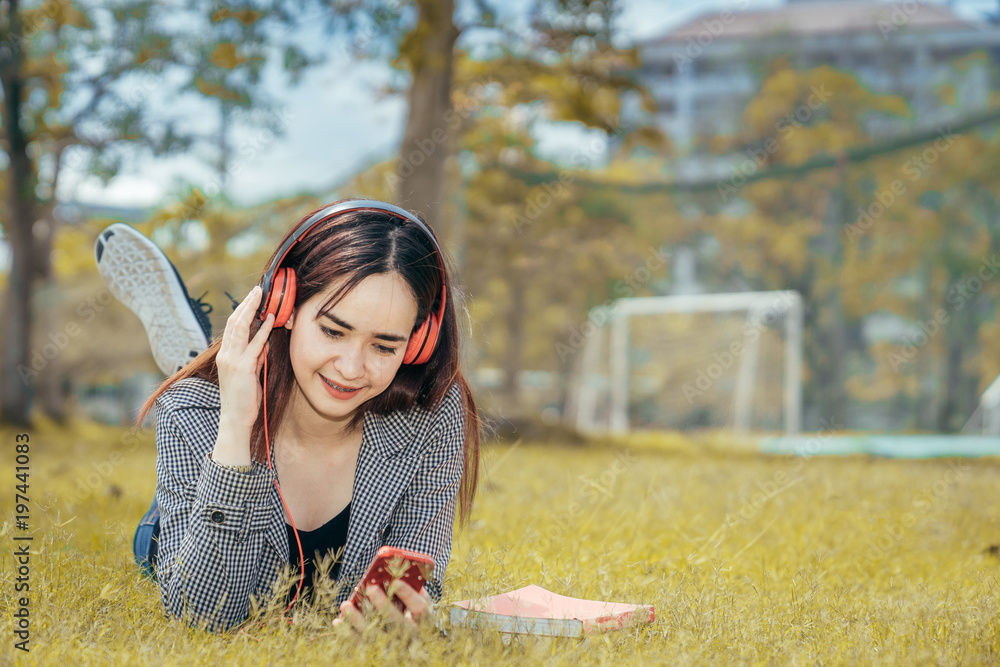 一个十几岁的大学生在暑假里微笑着看书。她在听