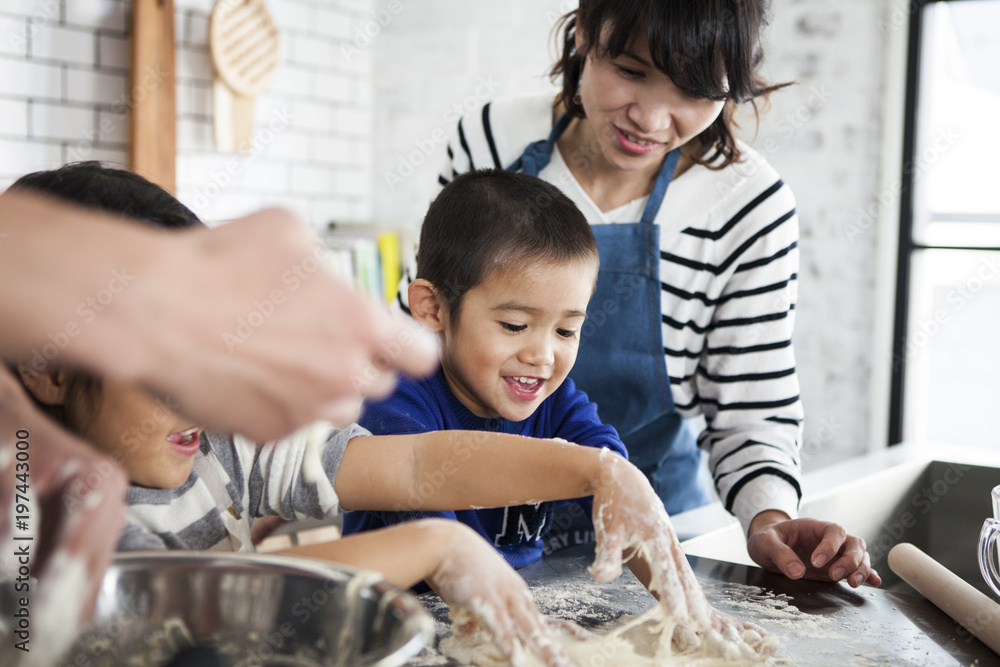 家族四人で仲良く料理を作っている。男の子と女の子はピザ生地をこねている。