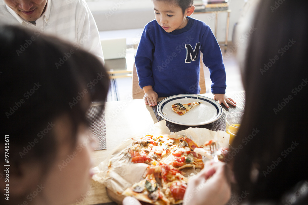 食卓。家族四人でピザを食べている。