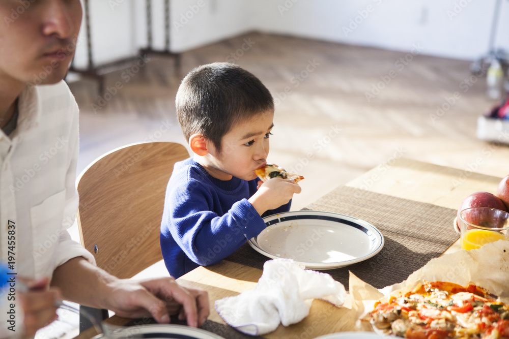 男の子がピザを食べている。