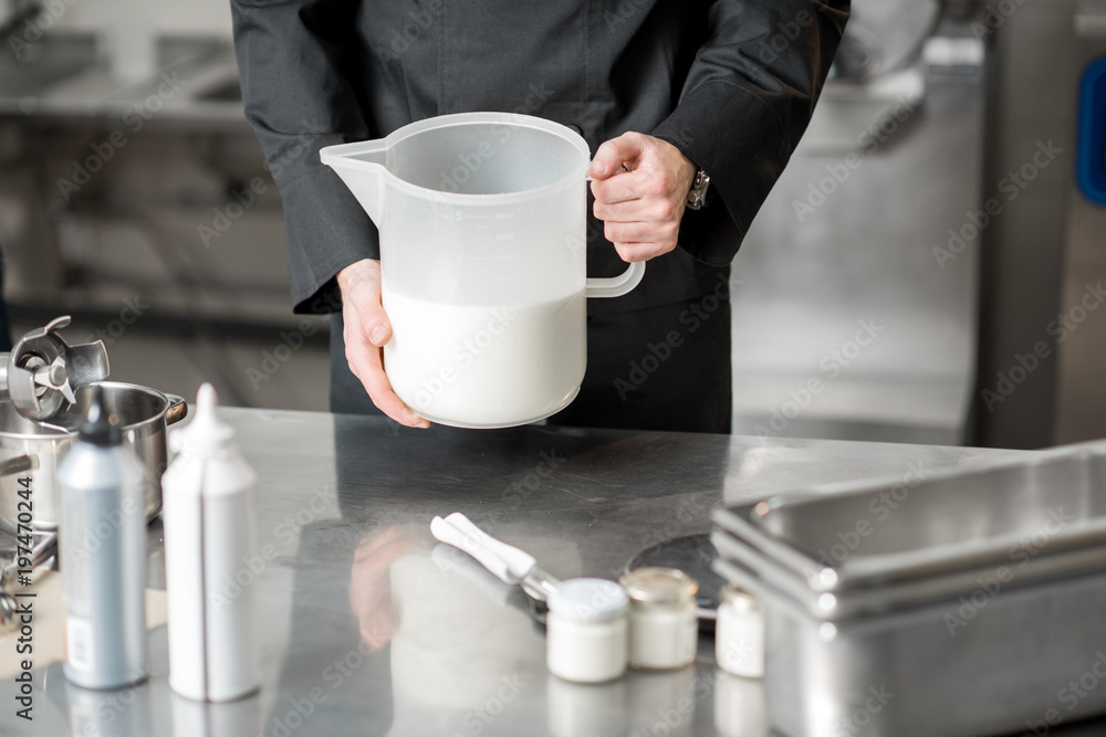 Chef holding a jar with milk prepairing basis for ice cream making