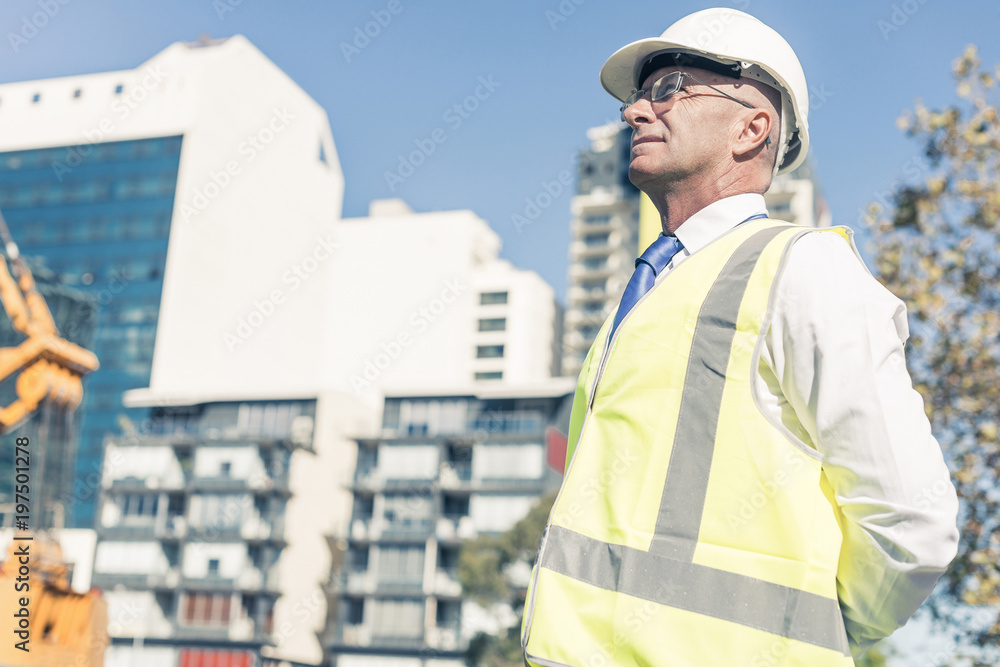 戴眼镜的高级工头在阳光下的建筑区工作