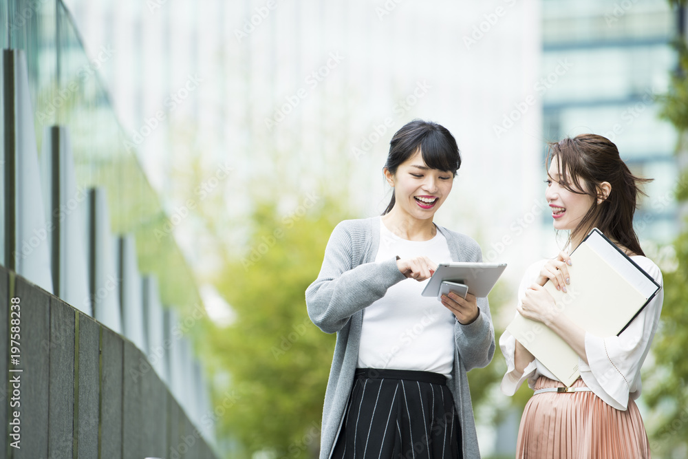 会話しながらタブレットを操作する女性社員たち