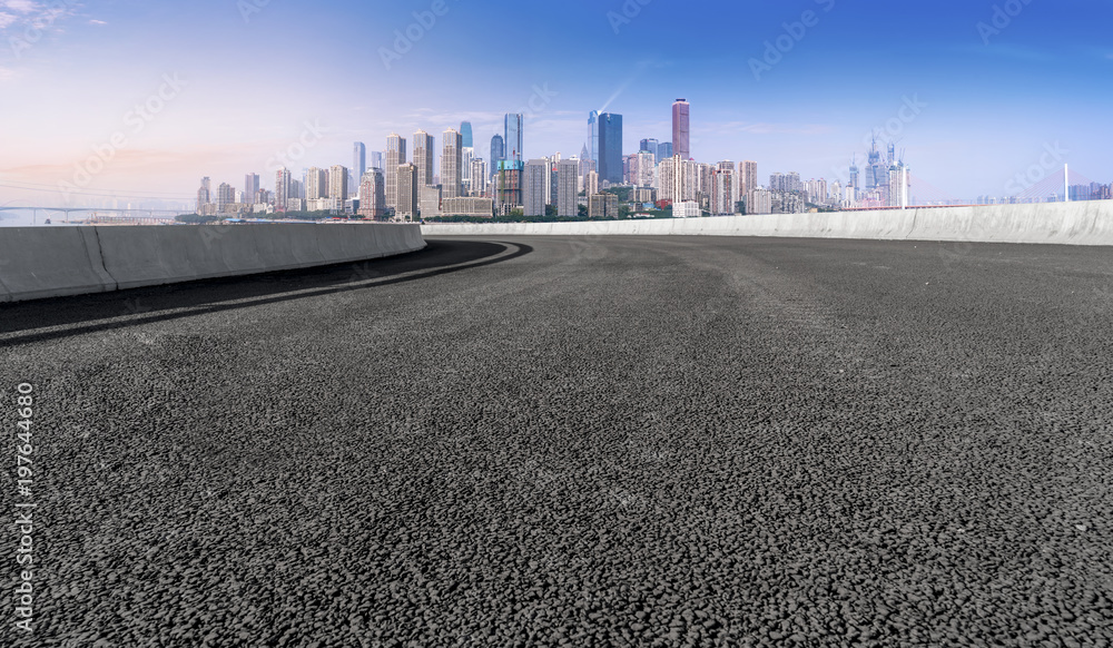 The empty asphalt road is along the modern commercial building in the Chinese city