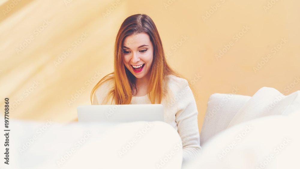 Happy young woman using her laptop computer at home