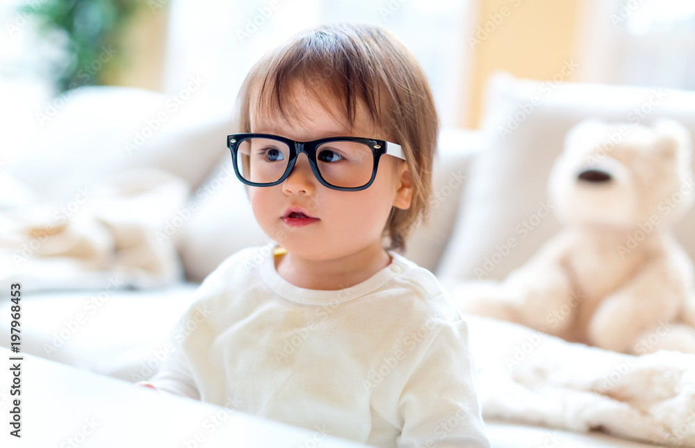 One year old toddler boy with eyeglasses in a living room