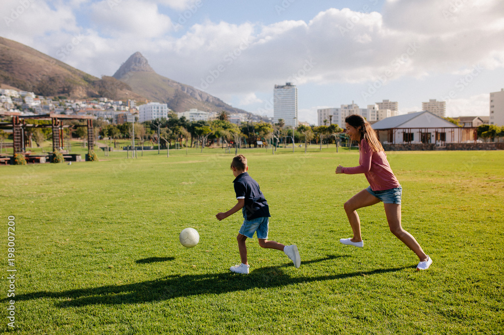 Mother and son playing football in park