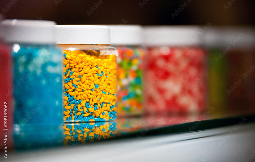 Jars with colorful candies on shelf at confecionery shop