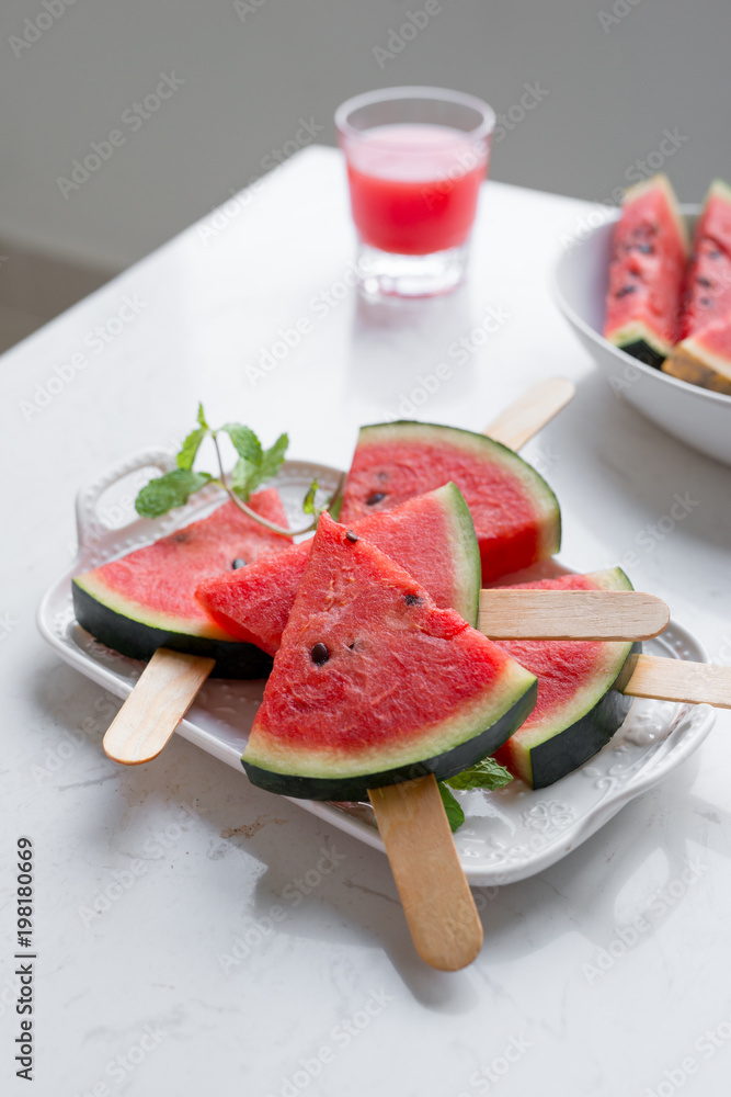 Fresh red smoothie in a glass with sliced pieces of watermelon on table.