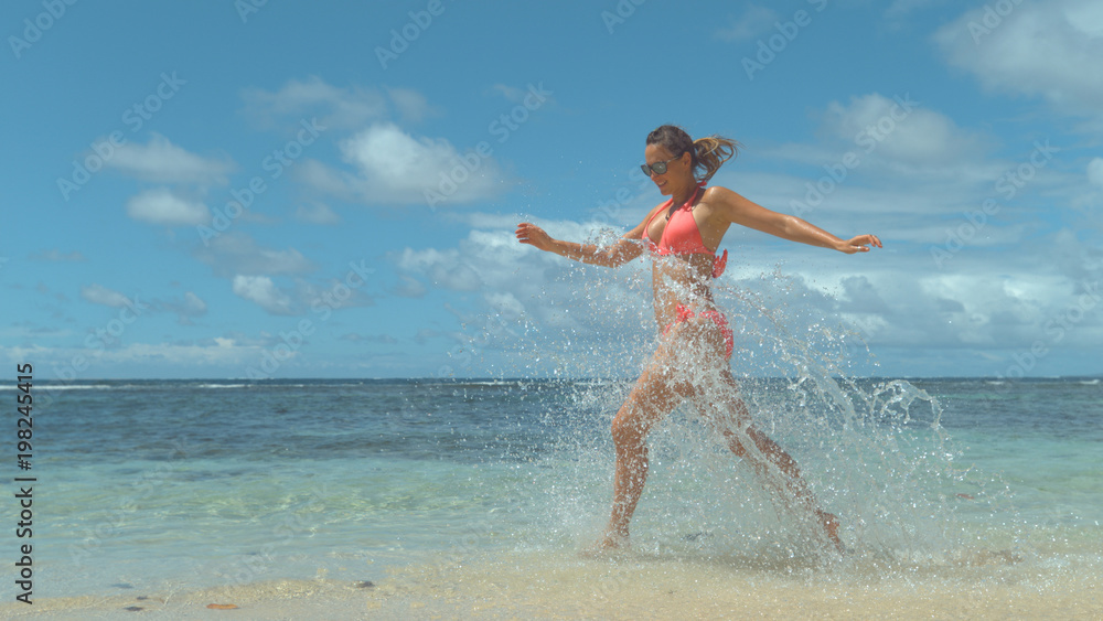 微笑的女人在海滩边玩耍，把清澈的海水溅得到处都是