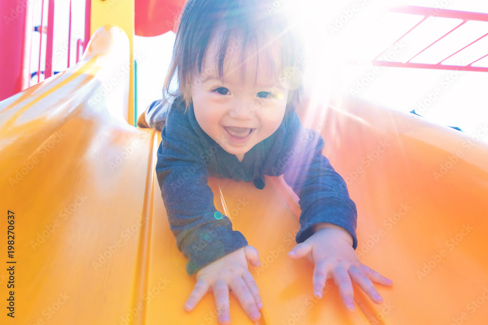 Mixed race toddler boy playing on a slide at a playground